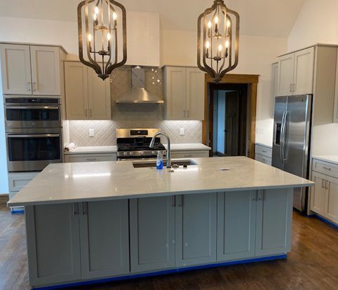 Rice Furniture & Design Center | custom built cabinets and island for kitchen with white backsplash and brass lights Rice Furniture & Design Center | custom built cabinets and island for kitchen with white backsplash and brass lights
